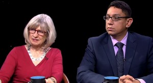 Two people sitting at a table with a cup of coffee.