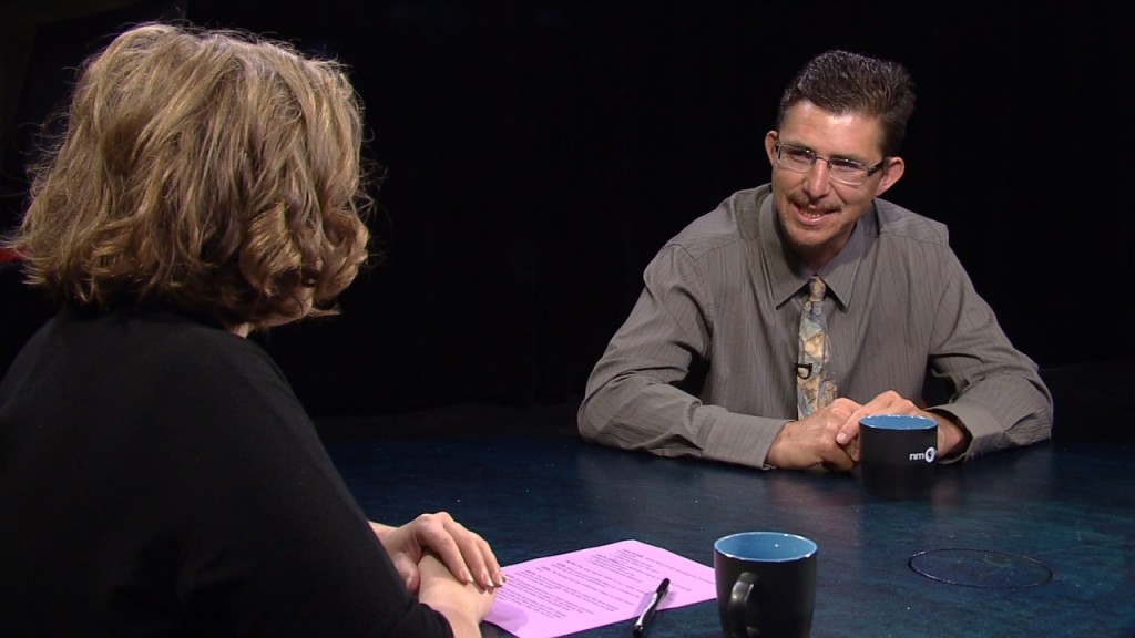 A man and woman sitting at a table talking.