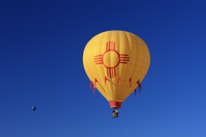 A yellow hot air balloon flying in the blue sky.