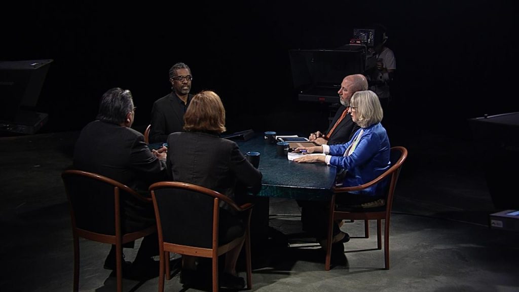 A group of people sitting at a table in a dark room.