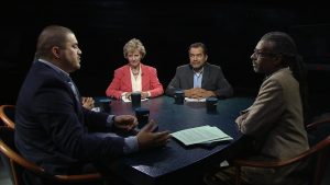 Four people sitting around a table in a dark room.