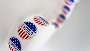A string of "I VOTED" stickers on a white backdrop.