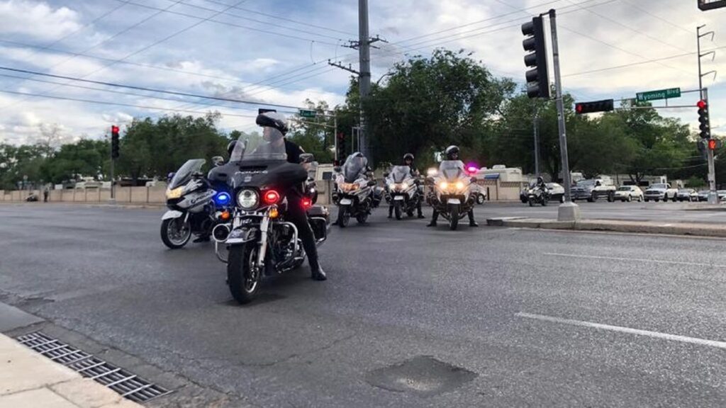 Cops on motorcycles sit in the middle of a street.