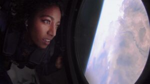 A woman looks out of a window down at Earth from a Virgin Galactic craft.