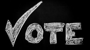 A black chalkboard with the word "vote" written in chalk.