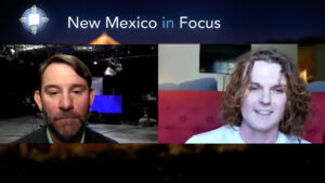 Two people are shown speaking during a virtual interview on a program titled "New Mexico in Focus." The backdrop includes a studio setting and indoor environment.