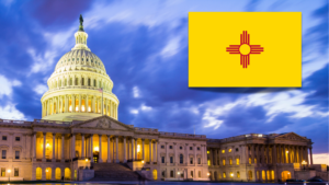 The U.S. Capitol building at dusk with the New Mexico state flag in the top right corner.