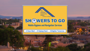 A "Showers to Go" sign for mobile hygiene services, by The Interfaith Community Shelter, against a blurred cityscape at dusk.